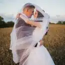 smiling newly wed couple about to kiss in green field