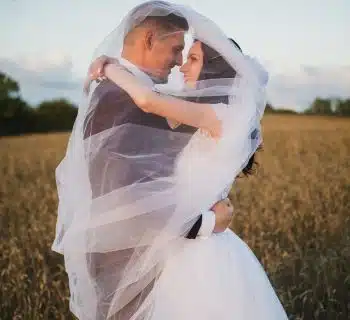 smiling newly wed couple about to kiss in green field