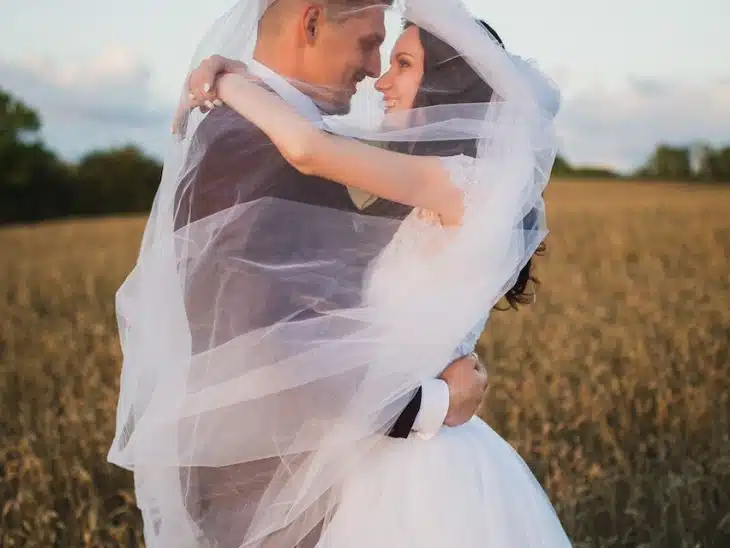 smiling newly wed couple about to kiss in green field